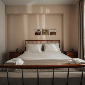 Un dormitorio con una cama grande, dos mesitas de noche y tres obras de arte colgadas en la pared.
