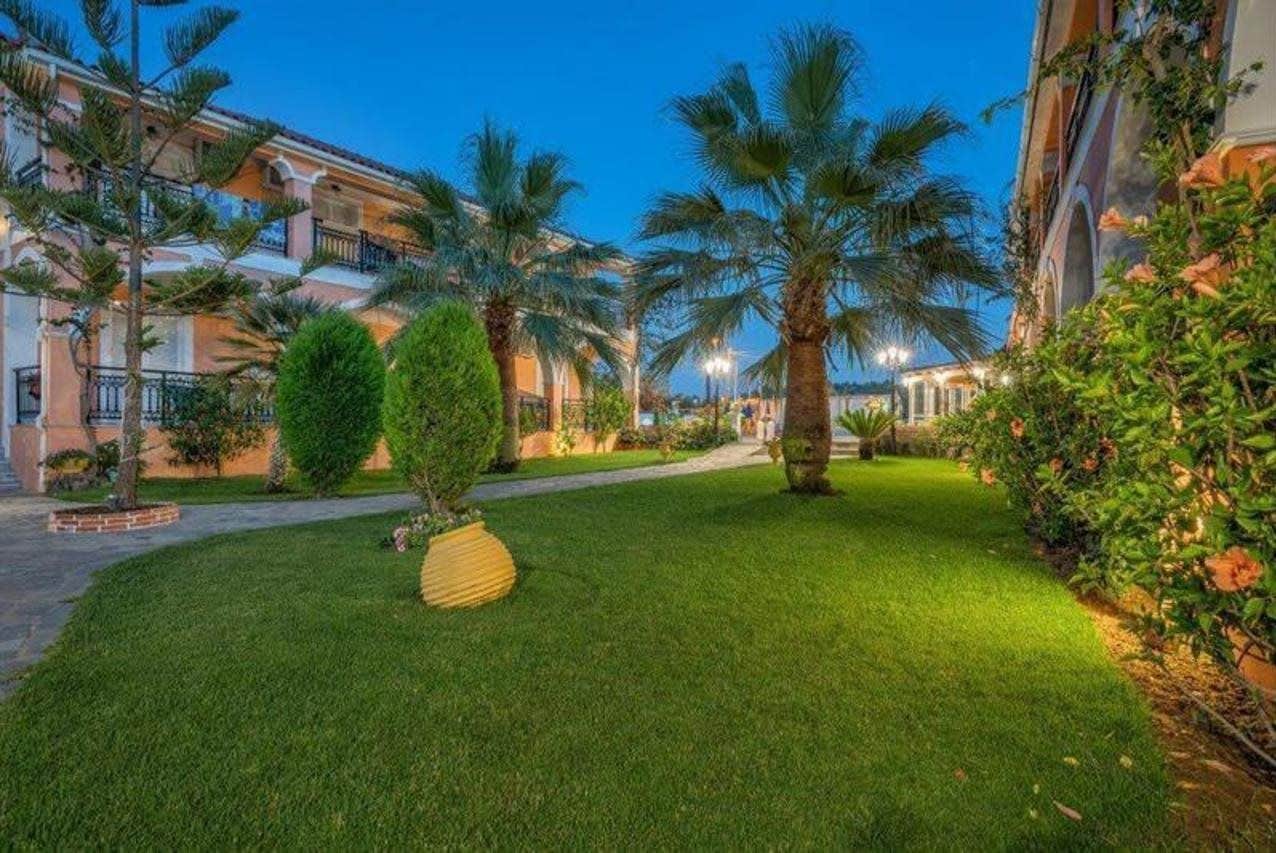 A well-maintained courtyard with palm trees, a neatly trimmed lawn, and a building with balconies.