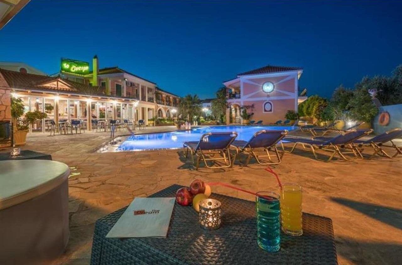 An outdoor pool area with lounge chairs, a bar, and a restaurant with outdoor seating.