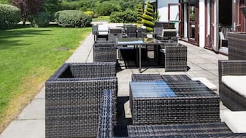 An outdoor seating area with wicker furniture and a view of the surrounding greenery.