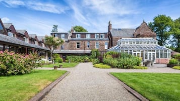 A traditional building with a central courtyard, surrounded by well-maintained gardens and a gravel pathway.