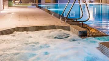 A hot tub area with a tiled edge and a metal ladder leading into a pool.