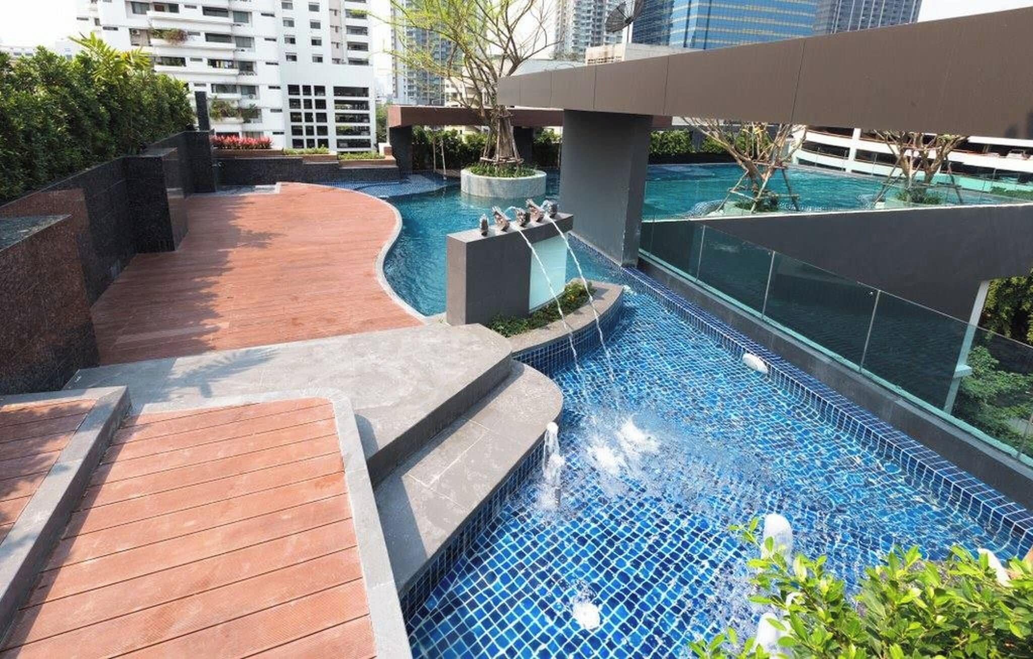 A rooftop swimming pool with a wooden deck and a modern architectural design.