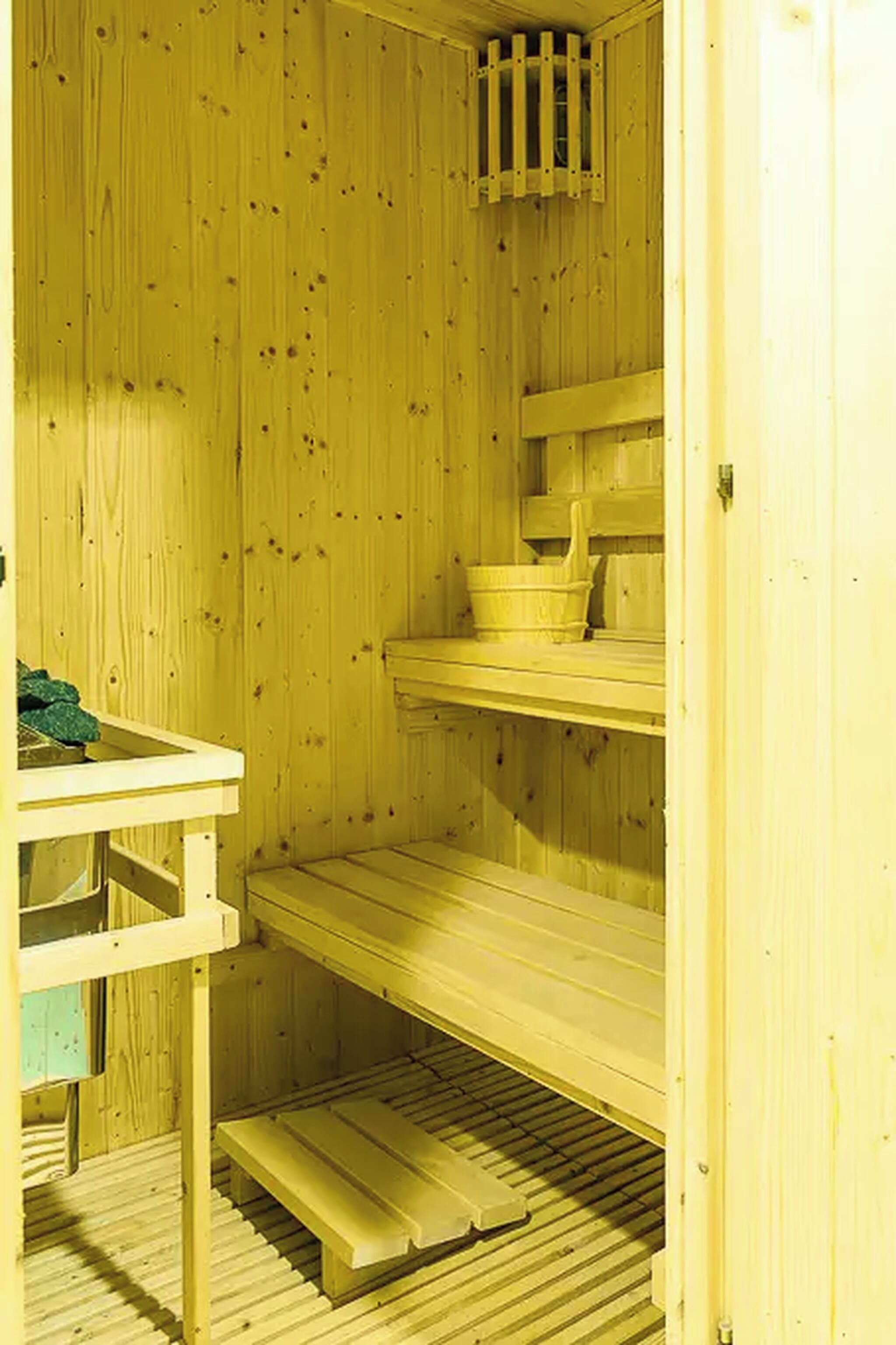 Una sala de sauna con paredes de madera y un banco.