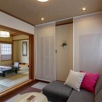 Una habitación japonesa tradicional con suelo de tatami, una mesa baja y un sofá con cojines.