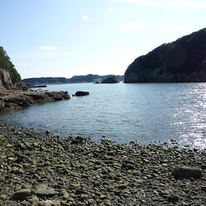A rocky shoreline with calm water, distant hills, and a clear sky. - Hotel Nagisaya (Nachikatsuura)