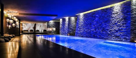 A spa area with a pool, stone walls, and a ceiling light fixture.