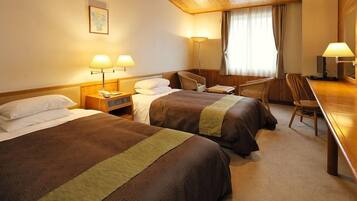 A hotel room with two beds, a desk, a chair, and a large mirror.