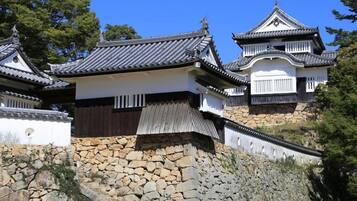 A traditional Japanese building with multiple levels, stone walls, and a steeply sloped roof.