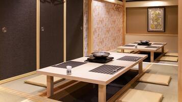 A traditional Japanese-style room with tatami flooring, a low table with a bowl and chopsticks, and sliding doors.