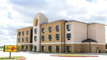 Um hotel Super 8 com vários andares, telhado plano e uma placa de identificação.