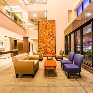 A lobby with a seating area, a wooden wall, and a glass railing.