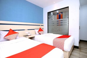 Habitación de hotel con dos camas, un amplio ventanal corredera y pared azul.