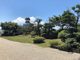 A building with a dome and a gravel path leading to it, surrounded by trees and shrubs.