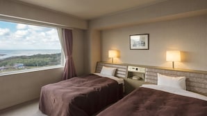 Une chambre d’hôtel avec deux lits, une fenêtre donnant sur un paysage agréable, une table de chevet et une lampe.