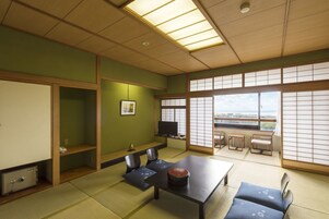 Una habitación tradicional japonesa con suelo de tatami, una mesa baja y un televisor.