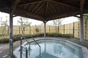 Una piscina exterior cubierta con escalera metálica, rodeada por una valla y árboles.