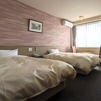 A hotel room with two beds, a framed picture on the wall, and a window with curtains.