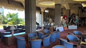 Un hall d’hôtel comprenant des espaces de détente, un comptoir d’accueil et une grande fenêtre donnant sur l’extérieur.