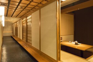 A corridor with sliding doors, a wooden bench, and a table with a teapot.