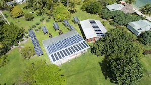An aerial view of a resort with solar panels, lush greenery, and a beach. - Nukubati Private Island Great Sea Reef (Nukubati Island)