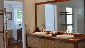 A bathroom with a large mirror, two sinks, and a herringbone-patterned vanity. - Nukubati Private Island Great Sea Reef (Nukubati Island)