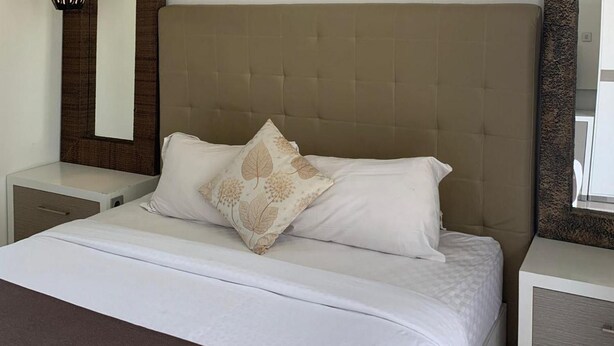 Quarto de hotel com uma cama grande, duas mesas de cabeceira e uma cabeceira.