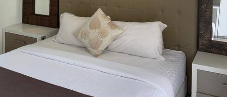 Una habitación de hotel con una cama grande, dos mesitas de noche y un cabecero.