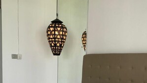 Quarto com cama, mesa de cabeceira e luminária na parede.