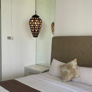 A bedroom with a bed, a nightstand, and a wall-mounted lamp. - Sawah Joglo Boutique Villas And Resto (Ngaglik)