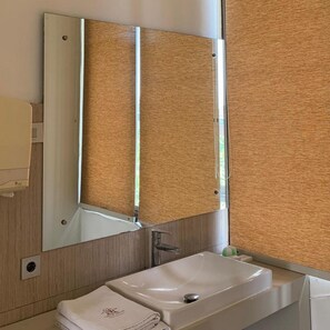 A bathroom with a white sink, a mirror, and a towel. - Sawah Joglo Boutique Villas And Resto (Ngaglik)