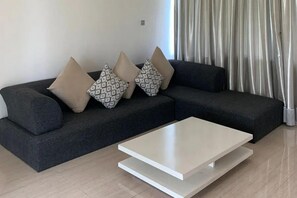 A modern living room with a dark grey sofa, patterned cushions, and a white coffee table. - Sawah Joglo Boutique Villas And Resto (Ngaglik)