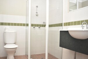 Un baño con inodoro, cabina de ducha y lavamanos.