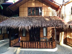 A thatched-roof structure with a covered outdoor seating area and a window. - Pyramid Alona (Panglao)