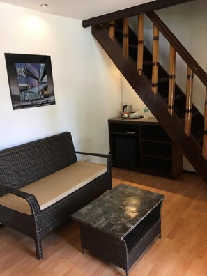Sala de estar com sofá, mesa de centro, quadro e escada.