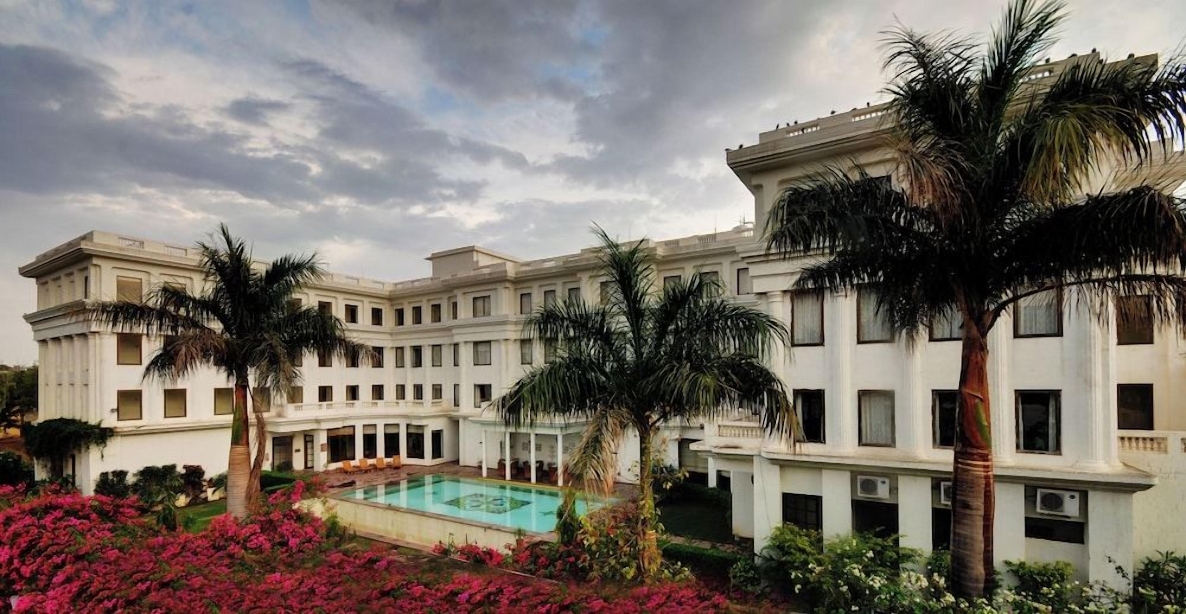 A large building with a pool and palm trees.