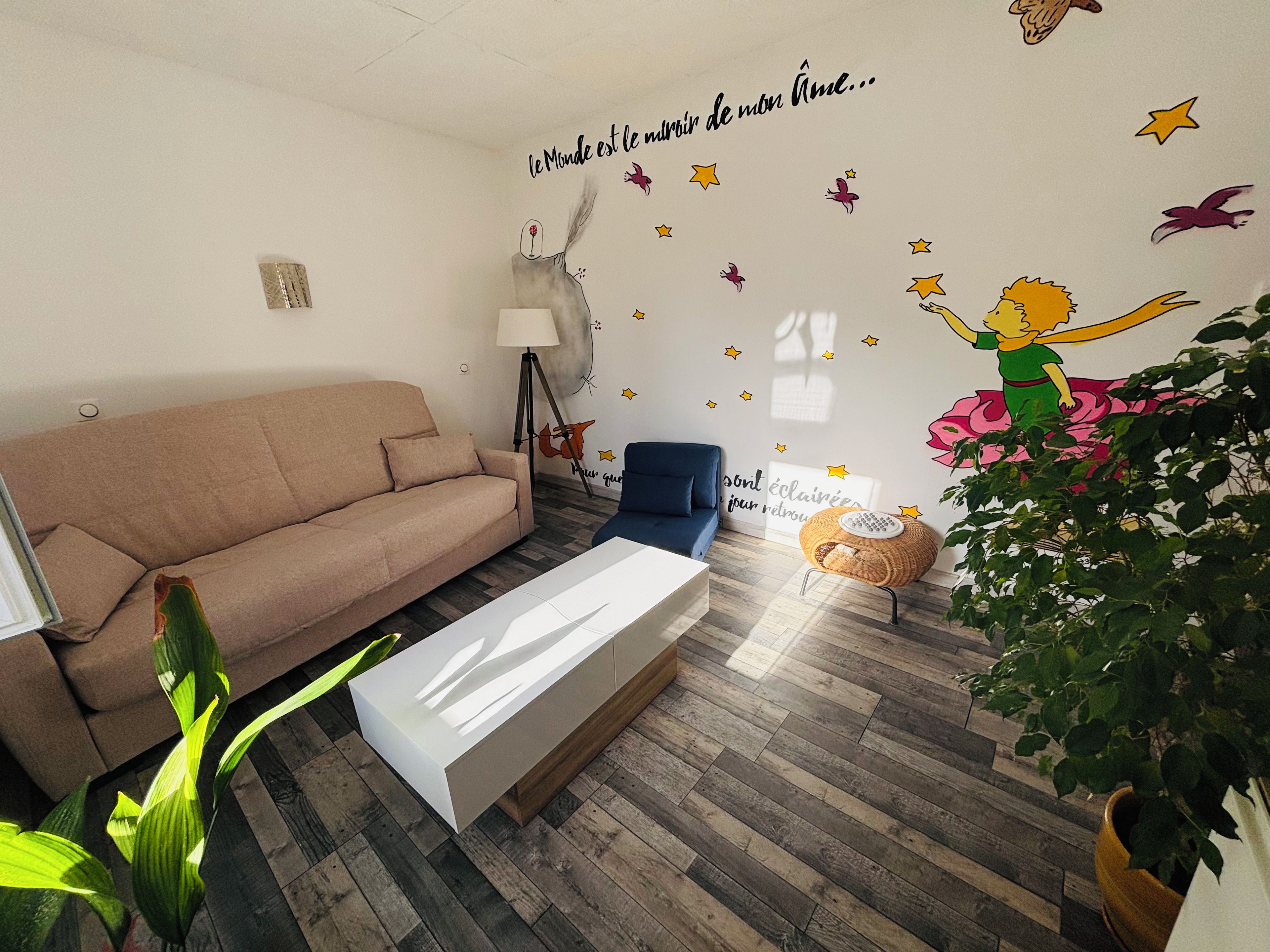 Ein Wohnzimmer mit einer Couch, einem Couchtisch, einer Lampe und einer Wand mit dekorativen Aufklebern.
