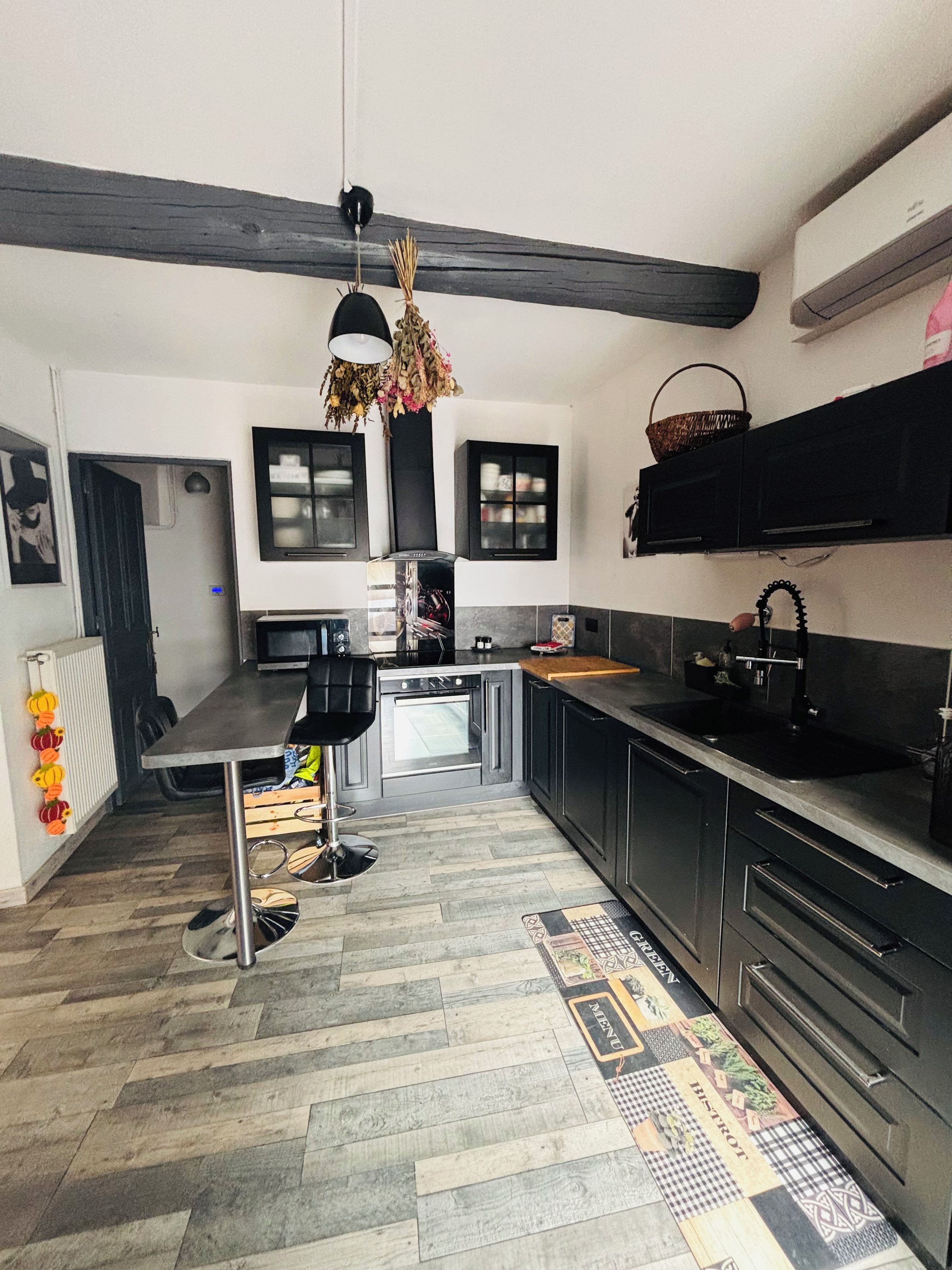 A modern kitchen with black cabinets, a central island, and a hanging light fixture.