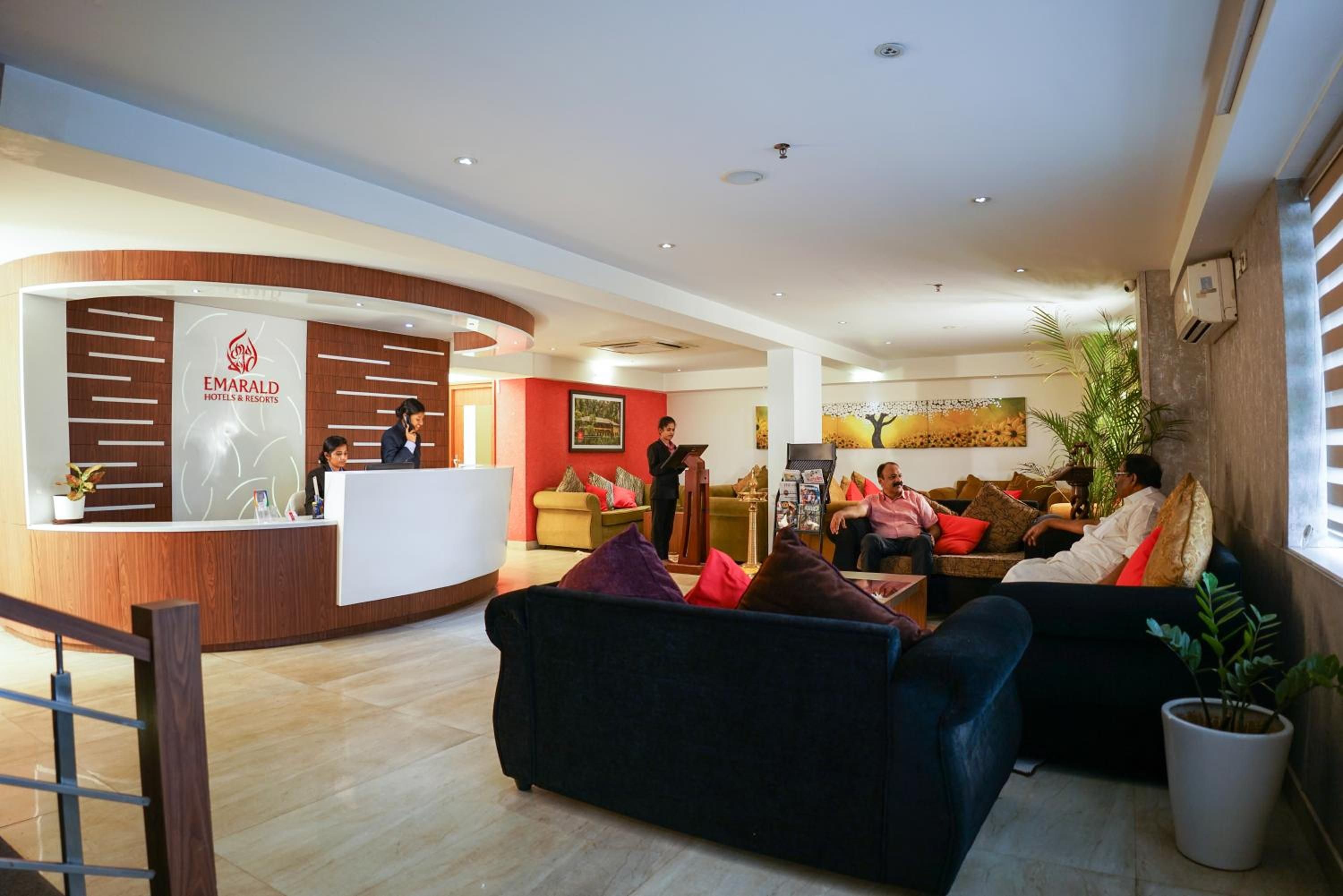 A hotel reception area with a reception desk, seating area, and a large window.