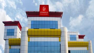 A hotel with a modern facade, featuring a prominent red and white sign with the name 'EMARALD HOTELS & RESORTS'.