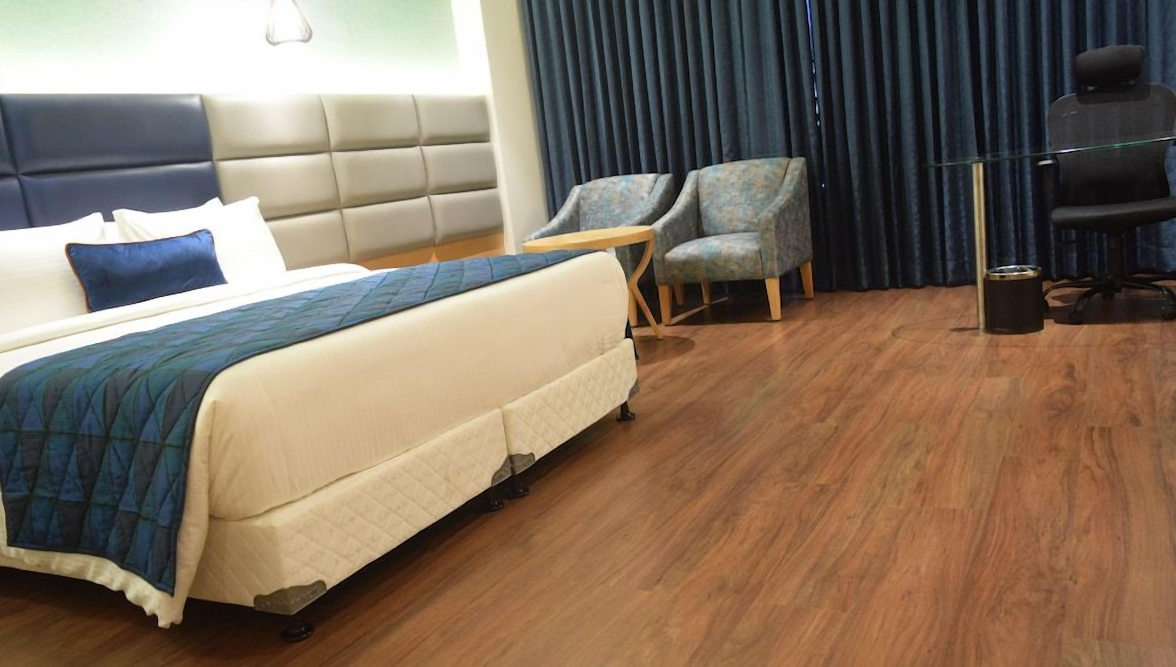 Ein Hotelzimmer mit einem Bett, zwei Sesseln, einem Schreibtisch und einem Papierkorb.