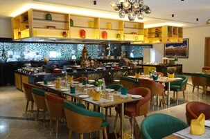 Un restaurante con varias mesas y sillas, una zona de cocina y estantes con diversos artículos.