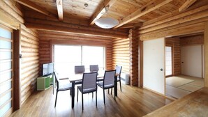 Interior de cabana de tronco com área de jantar, televisão e porta de correr.