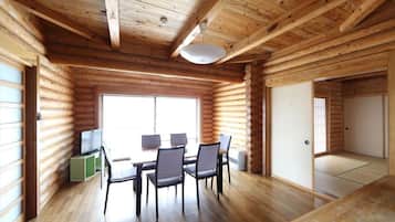 A log cabin interior with a dining area, a television, and a sliding door.