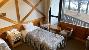 Quarto com cama, mesa de cabeceira e janela com vista para árvores.