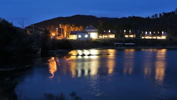 A lakeside property with multiple buildings, a dock, and a calm water body reflecting lights.
