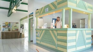Una zona d'entrada amb un mostrador, un home darrere seu i cartells informatius a la paret.