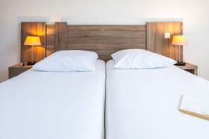 A double bed with white linens, two bedside tables with lamps, and a book on the bed. - Le Domaine De L'emeraude (Le Tronchet)