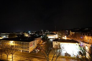Vista nocturna de un paisaje urbano con edificios, calles y coches estacionados.
