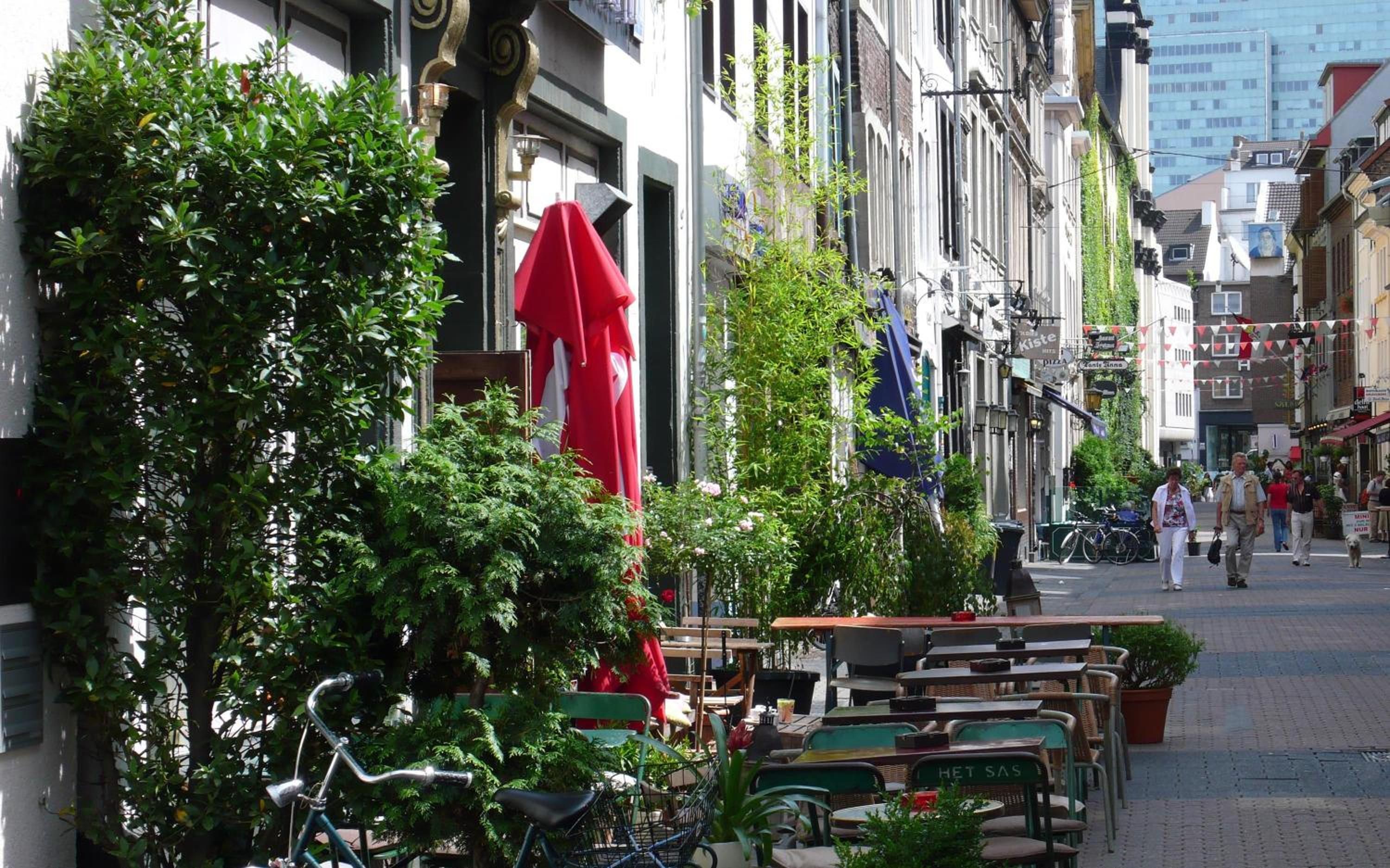 Une rue avec des terrasses, des vélos et des piétons.